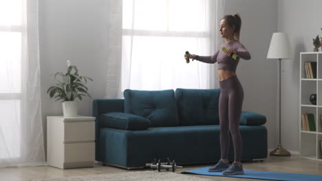 sport-and-fitness-at-home-young-woman-is-training-with-dumbbells-standing-in-living-room-of-her-modern-apartment-sporty-lady-in-interior